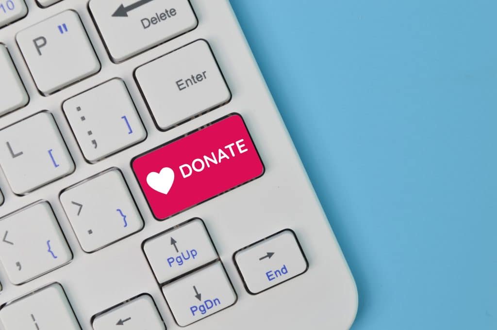 A laptop keyboard with a pink button labeled donate